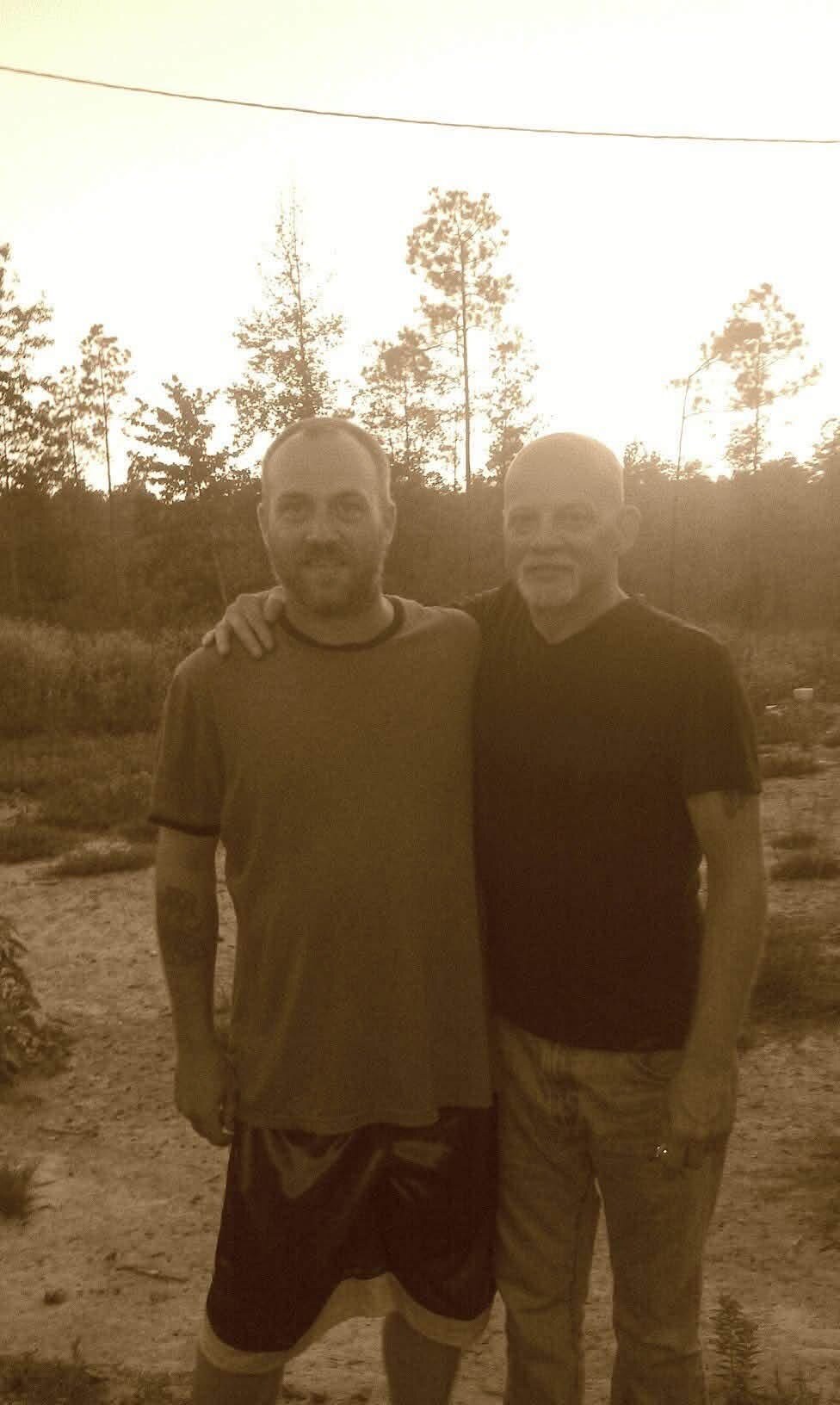 Two men standing together outdoors in warm sunlight